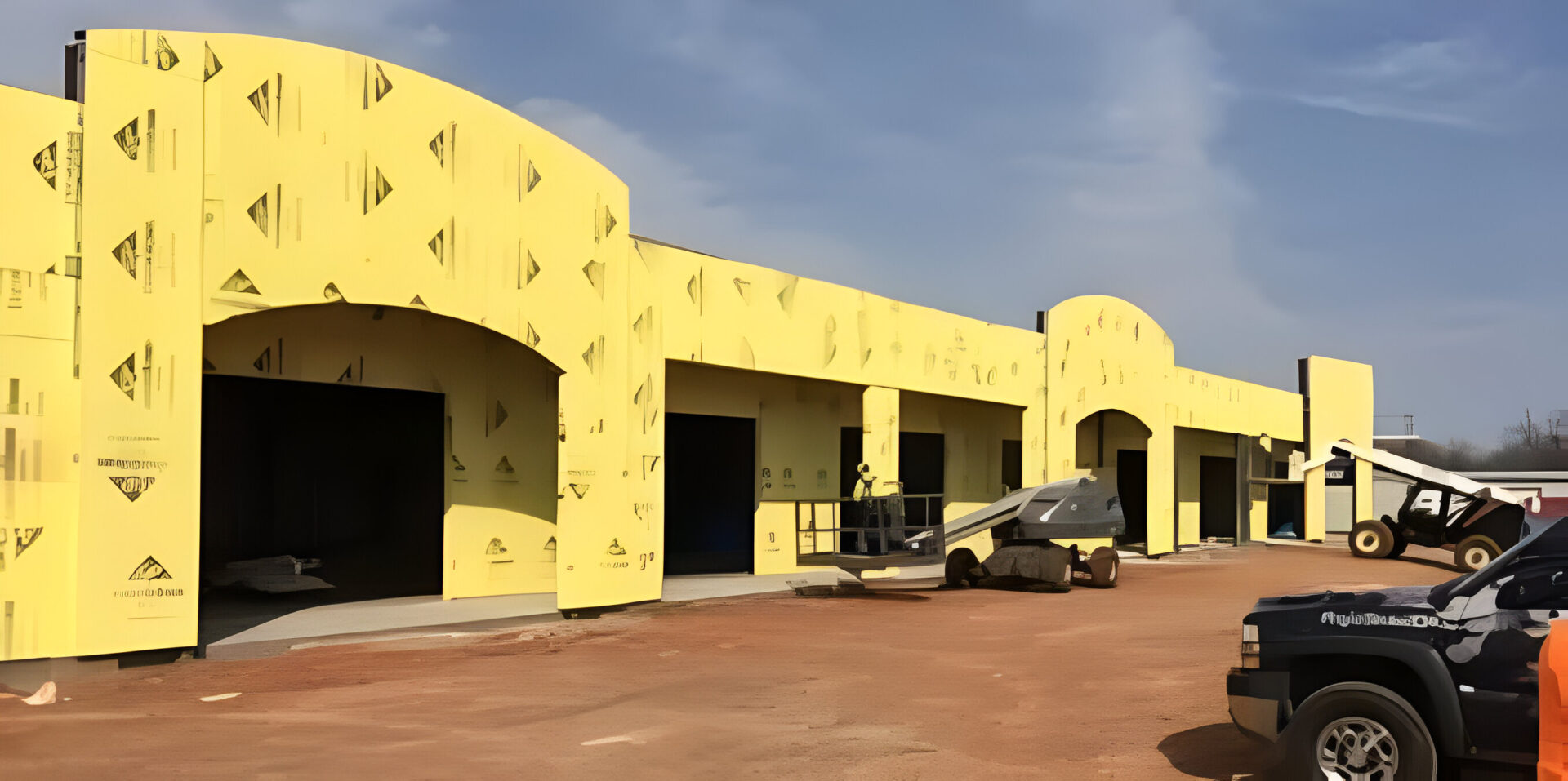 A car parked in front of a building with yellow walls.