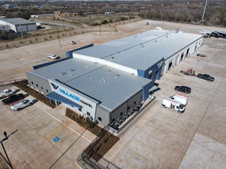 Aerial view of a PEMB with a standing-seam metal roof, drive-through service bays, and a paved lot, built for Village Travel in Oklahoma